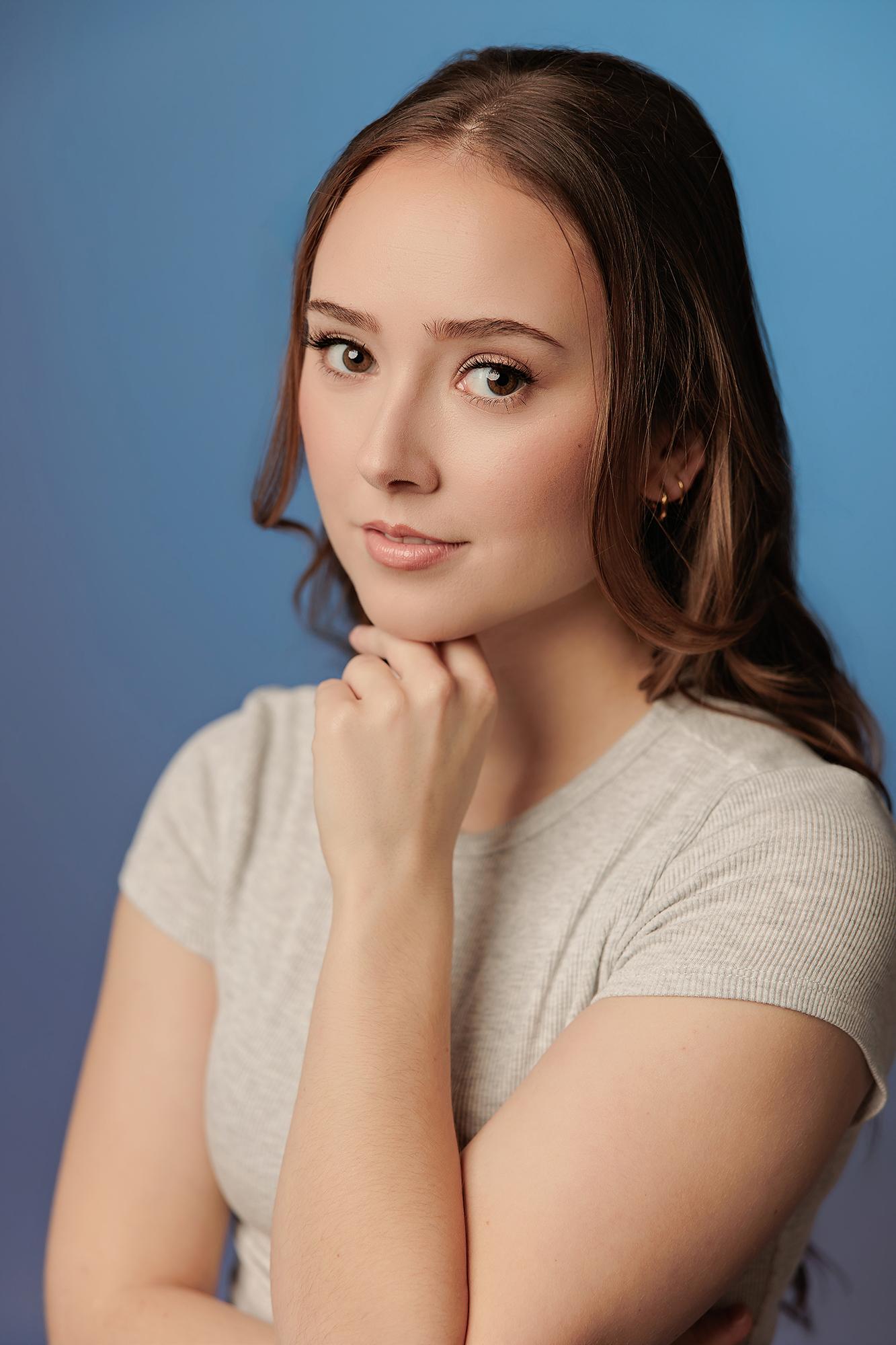 A young woman with a gentle expression rests her chin on her hand, showcasing the polished professional portrait style of our Calgary headshot studio.