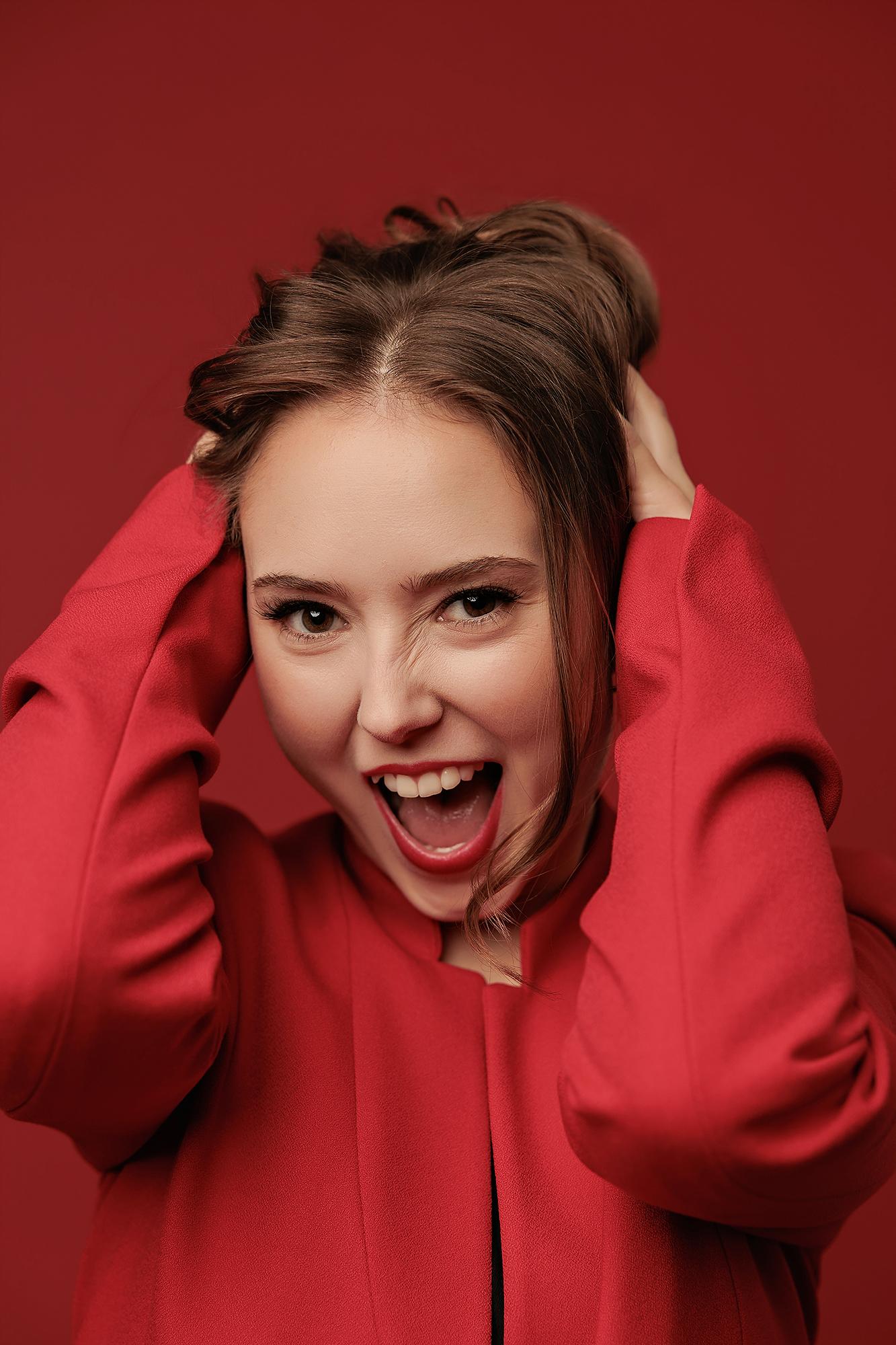 A woman in a vibrant red blazer poses with expressive energy for this Calgary headshot photographer, showcasing a bold personal branding style.