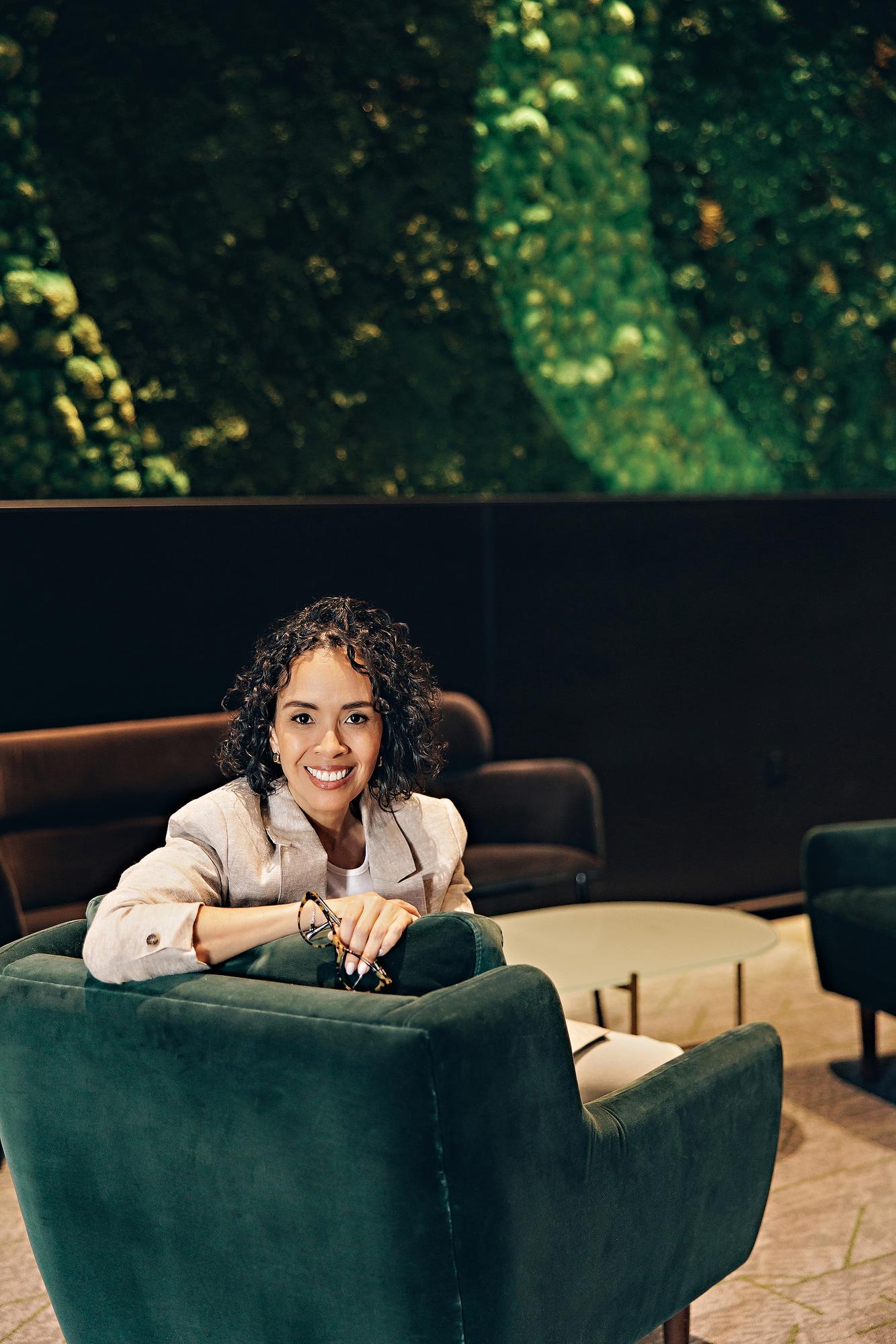 Executive headshot photography Calgary: Confident woman in a beige blazer leaning on a green velvet chair