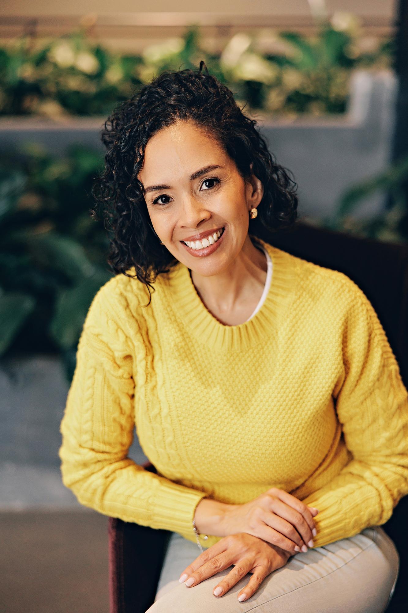 Professional headshot Calgary: Close-up portrait of a smiling female professional wearing a yellow cable-knit sweater