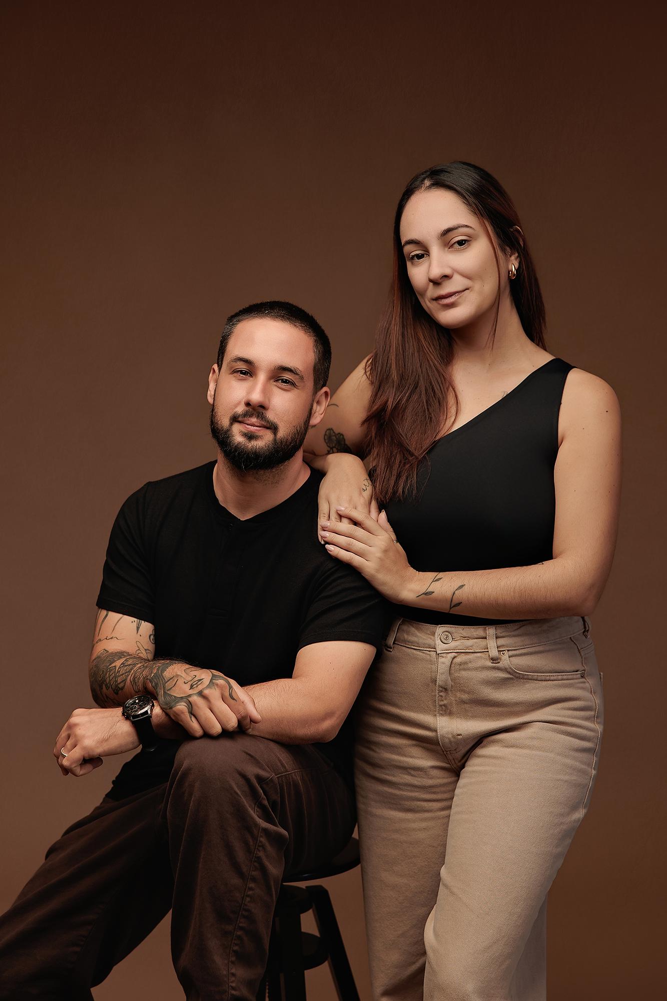 A man and woman pose for a professional portrait at our Calgary photography studio, featuring soft studio lighting against a warm brown backdrop.