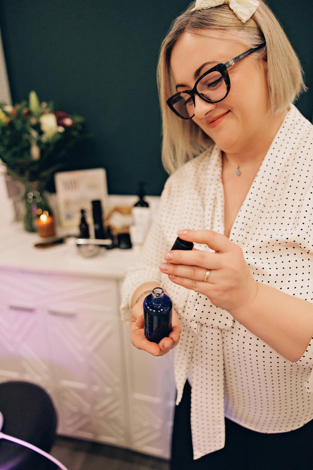 A woman in a polka-dot blouse uses a serum dropper in this personal branding session captured by a Calgary photographer in a bright, modern studio.