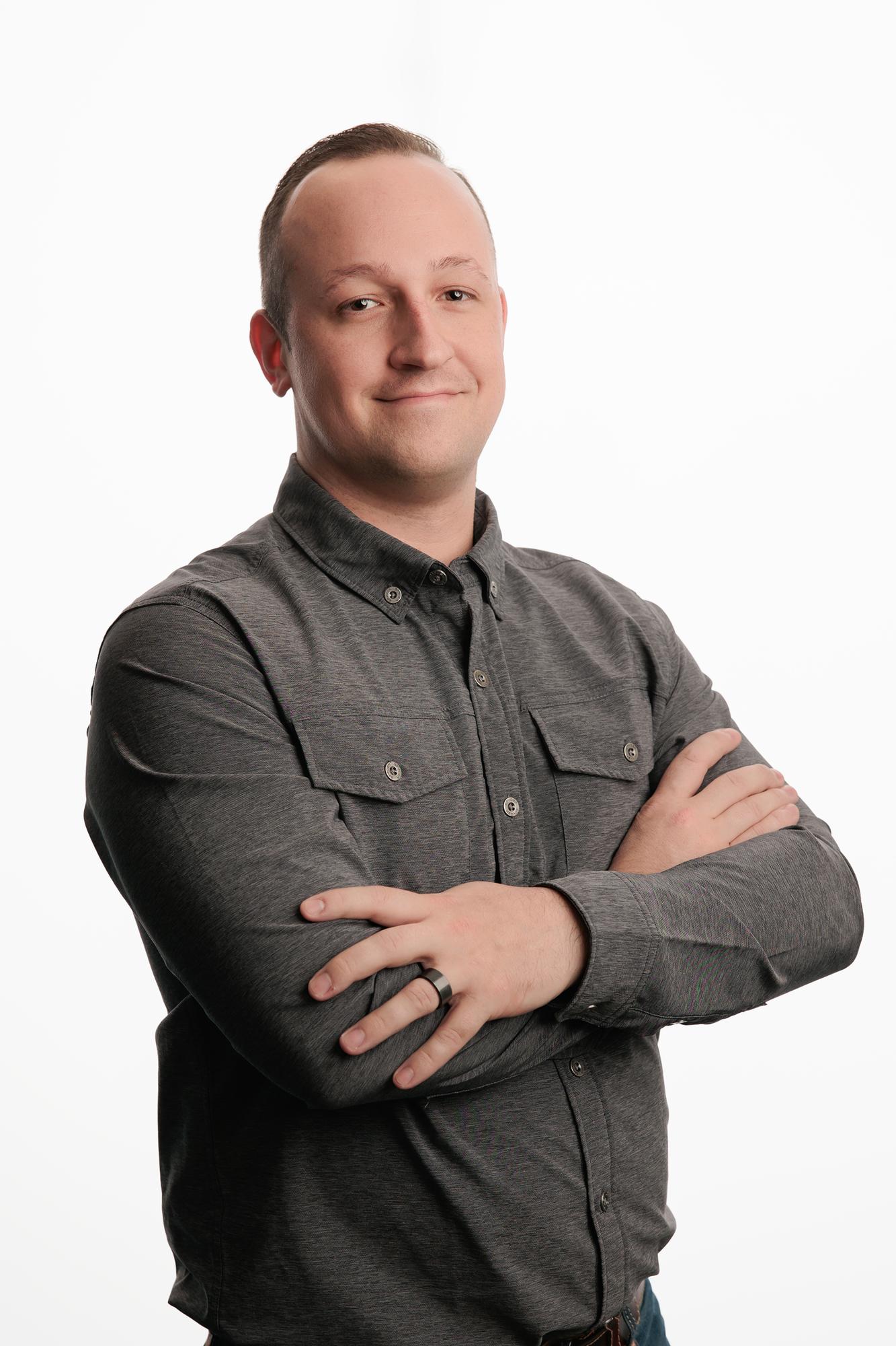 Team headshots Calgary studio: Professional man in a black double-breasted chef coat with a relaxed smile against a white background